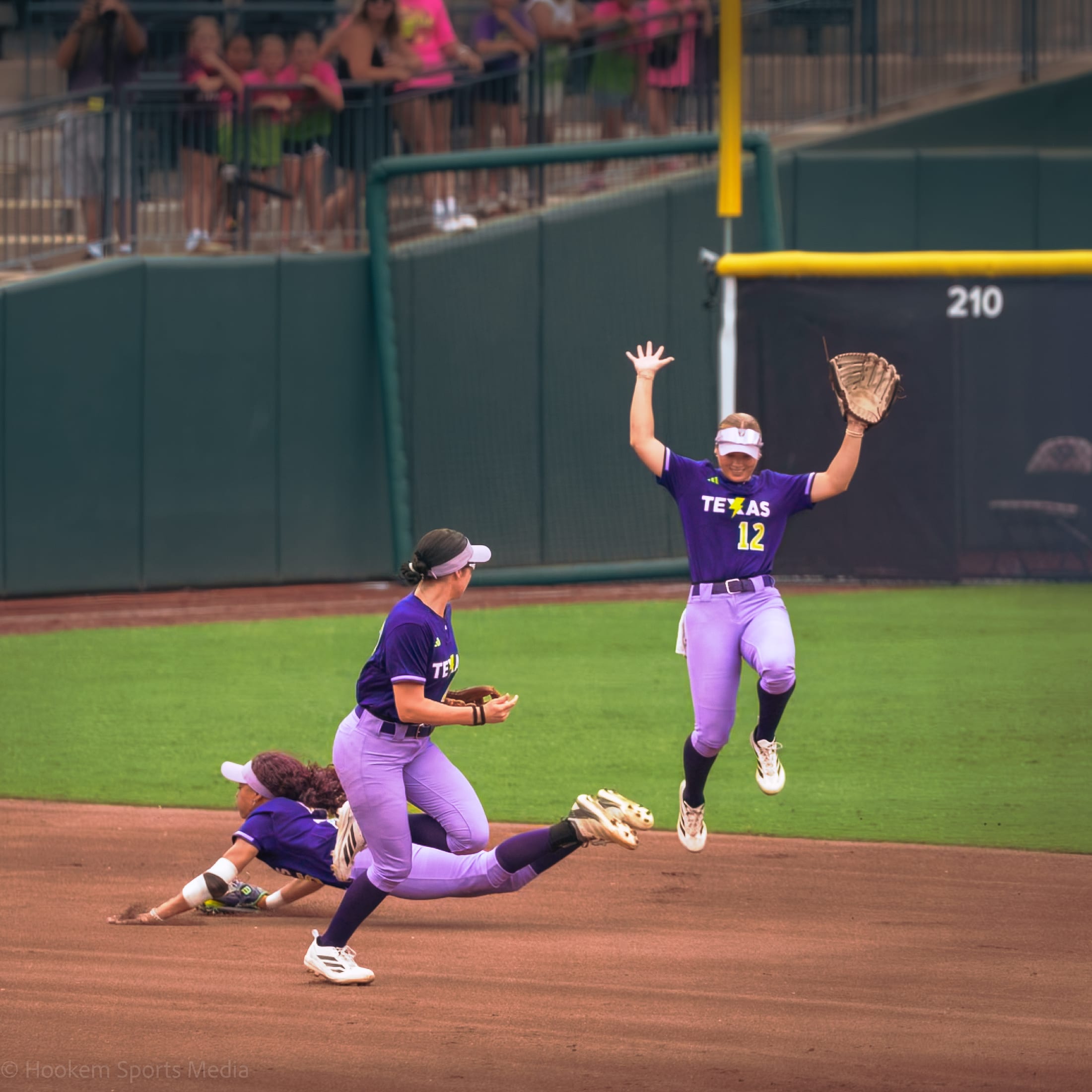 Rylie Boone, Jaydyn Goodwin, and Leighann Goode converge on the same fly ball at Dell Diamond.