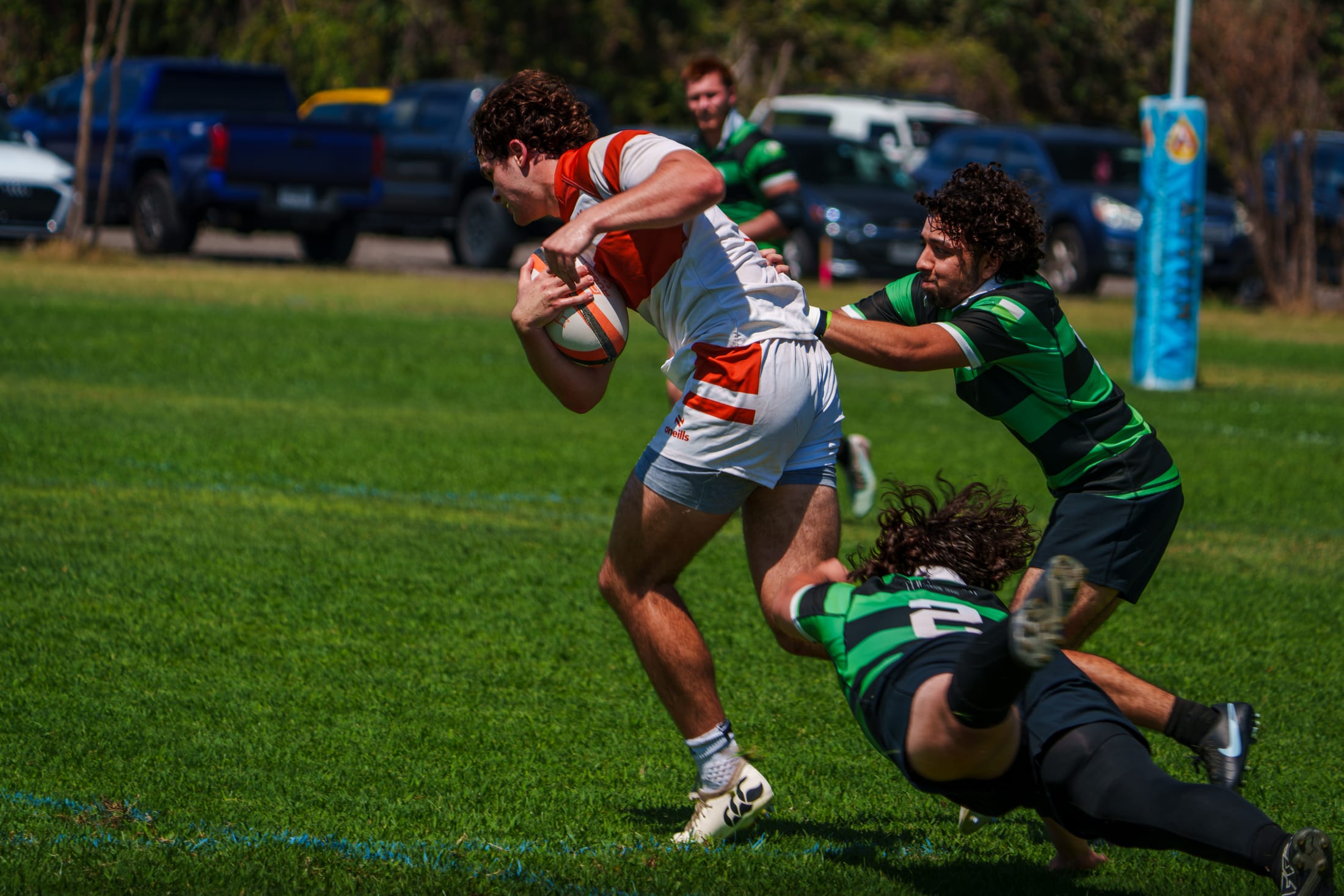 A Texas Rugby ball carrier drives forward as two North Texas tacklers close in at Huns Rugby Ranch.