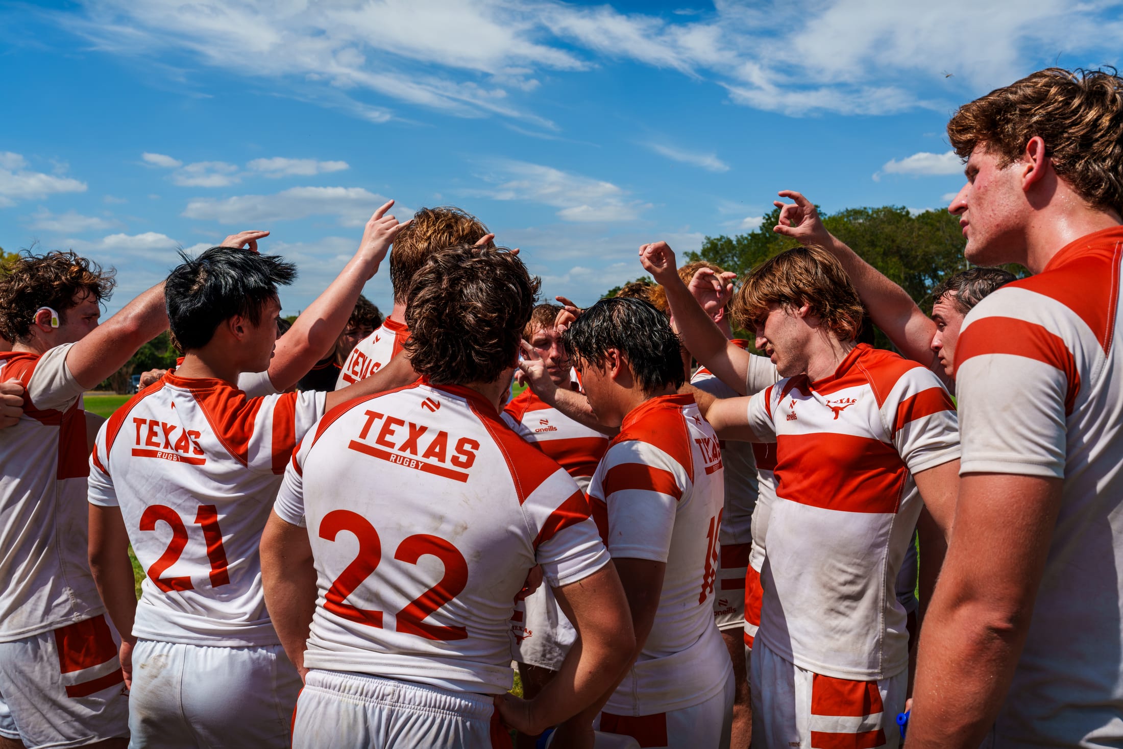 Texas Rugby huddles on the pitch with Hook 'em Horns raised after Lonestar Conference play at Huns Rugby Ranch.